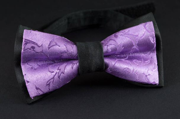 Фиолетовый галстук бабочка на черном фоне
 - Фото, изображение