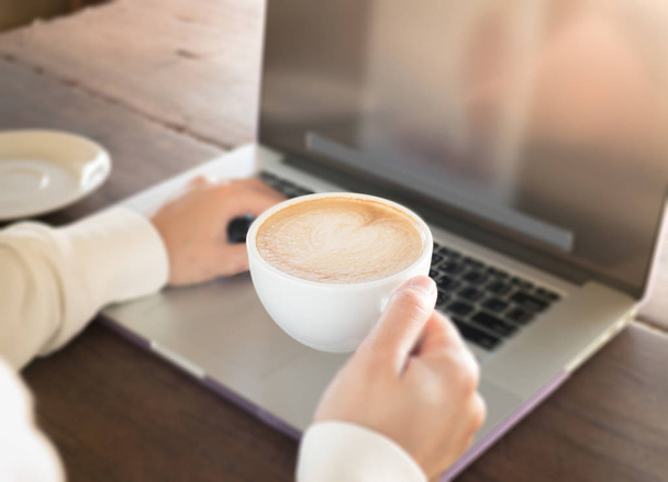 Frau arbeitet mit Laptop und heißem Kaffee - Foto, Bild