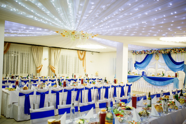 Hochzeitssaal mit Stühlen und Tisch mit blauen Bändern. - Foto, Bild
