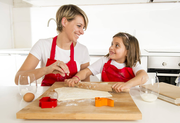 mladá matka a malá sladká dcera vaření v kuchyni připravuje pouštní váleček tyčinkou - Fotografie, Obrázek