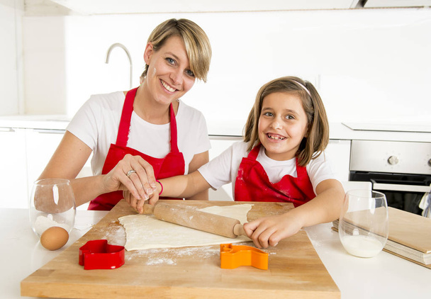 young mother and little sweet daughter cooking in kitchen preparing desert with rolling pin rod - Photo, Image