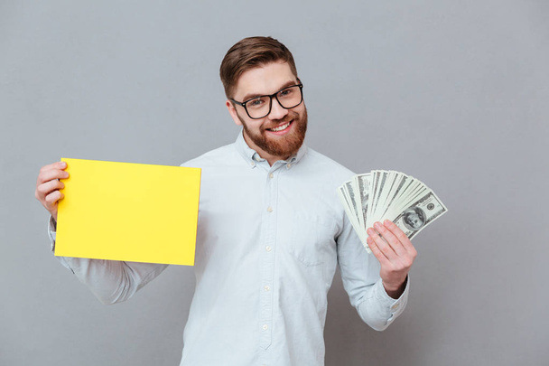 Happy bearded businessman holding copyspace blank and money - Foto, imagen