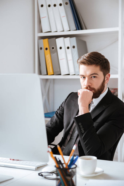 Bearded businessman sitting in office while using computer - Foto, Bild