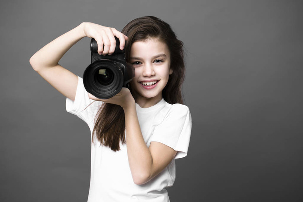 Cute brunette little girl holding an photo camera - Foto, imagen