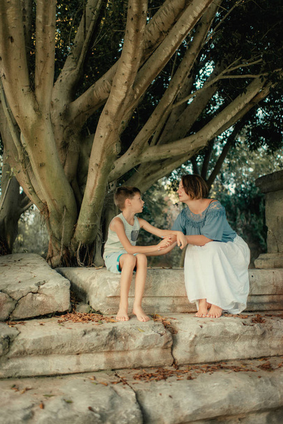 Moeder met kleine jongen in het park onder een boom - Foto, afbeelding