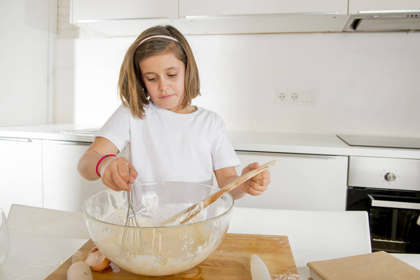 Mini šéfkuchař dívka smíchání mouky a vajec, pečení, přípravu sladkého poušť, usmíval se šťastný - Fotografie, Obrázek