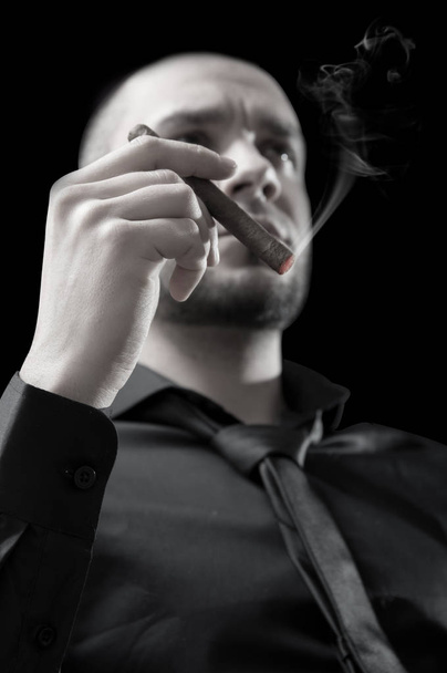 Businessman's hand with cigar on black background - 写真・画像