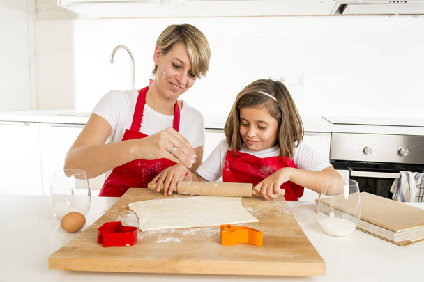 joven madre y pequeña hija dulce cocinando en cocina preparando desierto con barra de rodillo
 - Foto, imagen