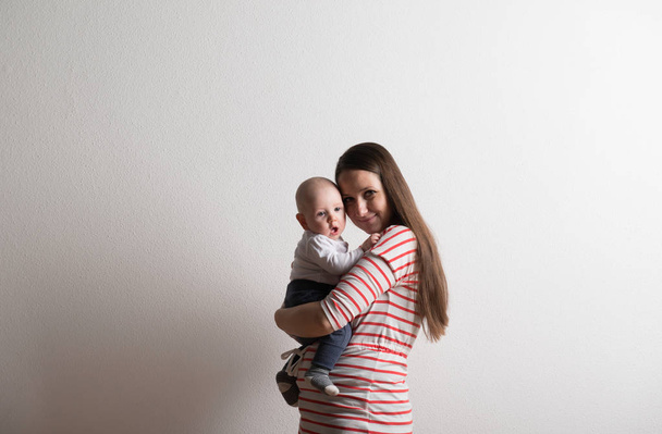 Beautiful mother holding baby son in her arms. Studio shot. - Foto, Imagem