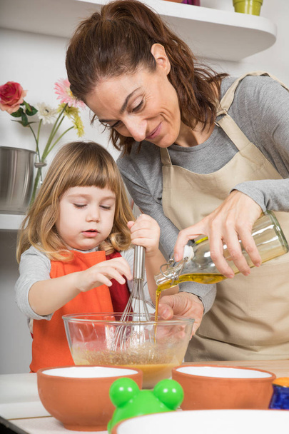woman pouring oil in bowl and child whipping - Photo, Image