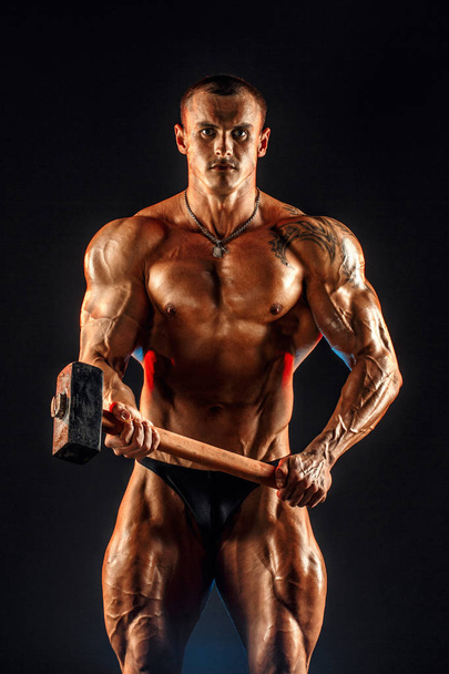Portrait of shirtless athlete with hammer on shoulder - Foto, afbeelding