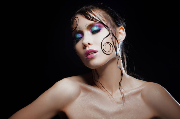 Young beautiful girl bright makeup with a wet look shine, dark background - Fotoğraf, Görsel