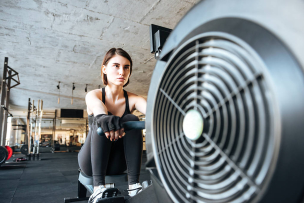 Woman athlete working out with training machine in gym - Foto, Imagem