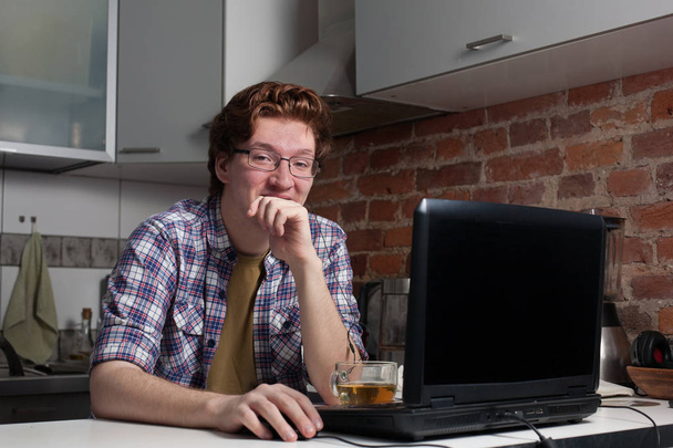 Молодой человек работает на ноутбуке. - Фото, изображение