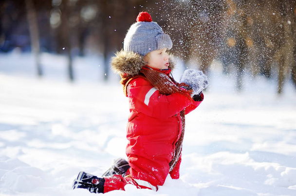 Little boy in red winter clothes having fun with snow - 写真・画像
