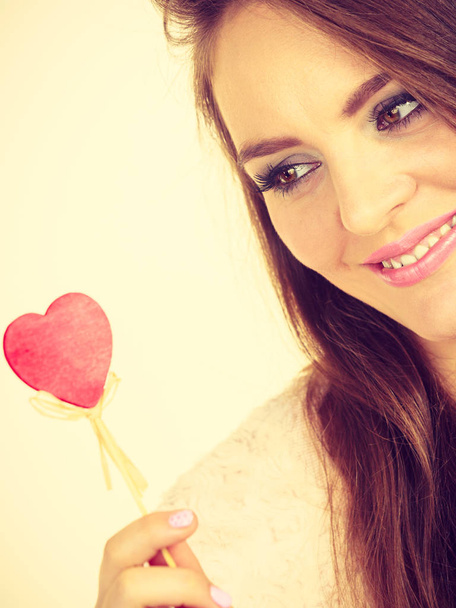Flirty woman holding red wooden heart on stick - Fotografie, Obrázek