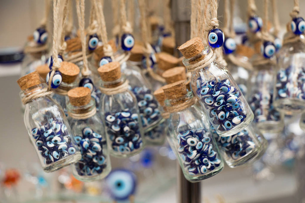 Pequeña botella de vidrio transparente llena de perlas azules del mal de ojo
 - Foto, Imagen