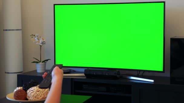 女性は緑色の画面でテレビのチャンネルをスイッチします。 - 映像、動画