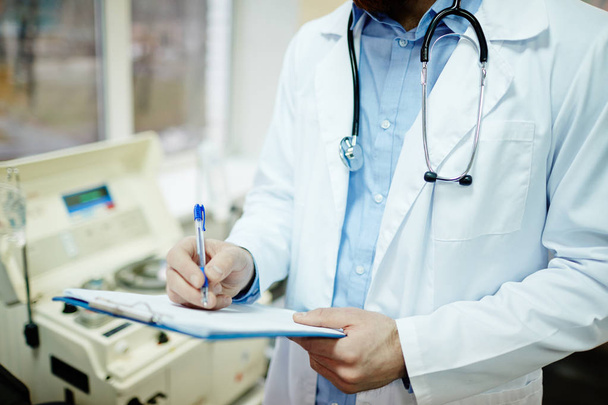 Arzt im weißen Kittel macht sich Notizen - Foto, Bild