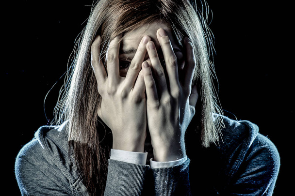 Teenagermädchen in Stress und Schmerz, die unter Depressionen leiden und traurig und verängstigt ihr Gesicht bedecken - Foto, Bild