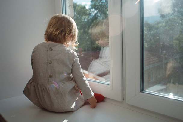 Küçük kız bir pencere üzerinde oturur - Fotoğraf, Görsel