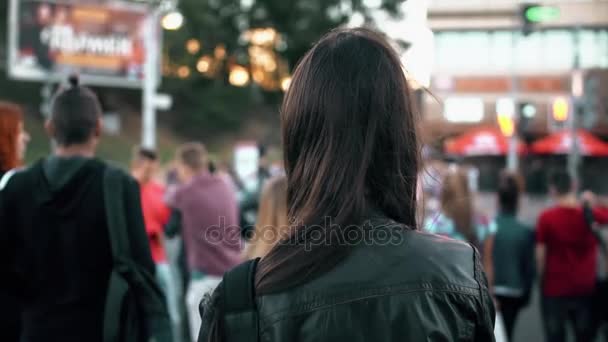 Молодая женщина, стоящая на улице, готовящаяся к перекрестку на светофоре, развевающиеся на ветру волосы. Вид сзади. Медленно
 - Кадры, видео