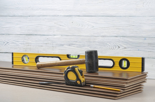 Carpentry concept.Different tools- level, tape-measure, rubber hammer on the new laminate flooring.Copy space for text
. - Фото, изображение