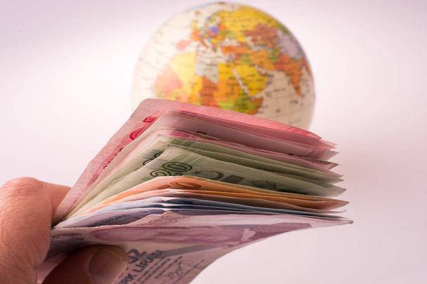 Billetes de mano de Lira turca al lado de un globo modelo
 - Foto, imagen