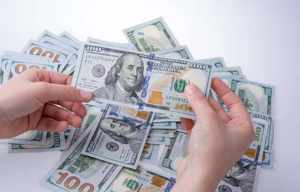 Mano humana sosteniendo billetes en dólares americanos sobre fondo blanco
 - Foto, imagen