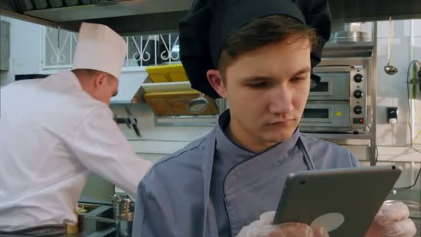 Böngészés a tabletta a kíváncsi fiatal szakács-gyakornok - Felvétel, videó