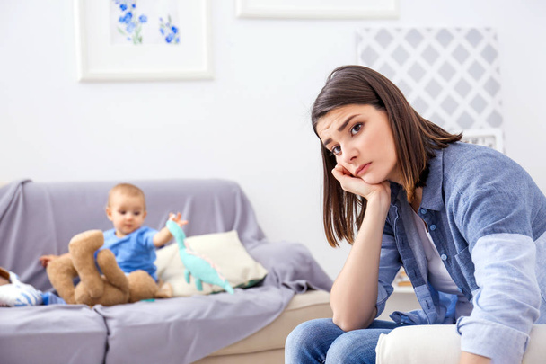 Depressed young woman with cute baby at home - Φωτογραφία, εικόνα