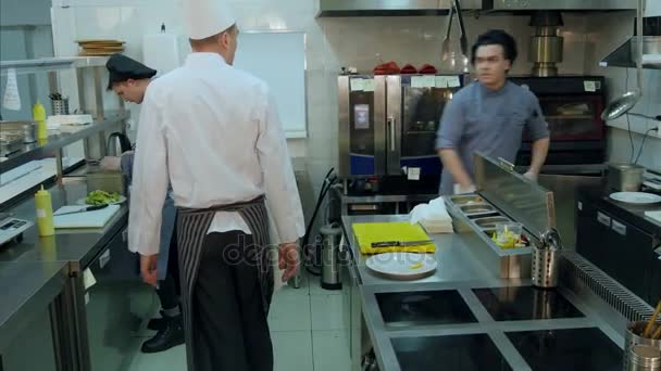 Šéf kuchař sledovat jeho asistenti pracují v kuchyni a že jim úkoly - Záběry, video