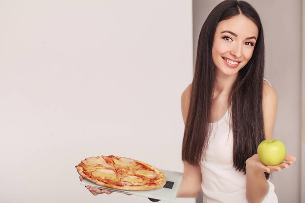 Дієта. Молода жінка тримає піцу на вагах. Концепція здорового харчування
 - Фото, зображення