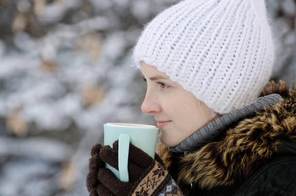 Mädchen mit weißem Hut im Winter mit Tasse Tee, Seitenansicht, Nahaufnahme - Foto, Bild