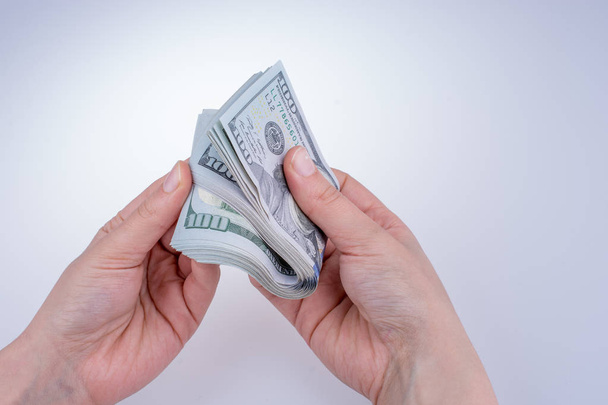 Main humaine tenant des billets en dollars américains sur fond blanc
 - Photo, image