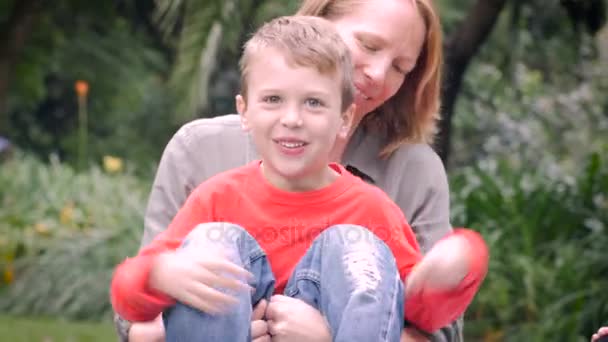 A mother holds her young cute son and kisses him with lens flare - Filmagem, Vídeo