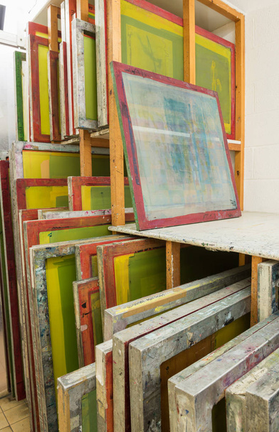 Silk screen printing screens stored in a wooden rack ready for printing. - Fotó, kép