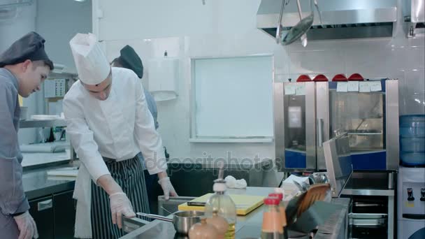 Чоловік зрілий шеф-кухар показує свою стажистку навколо кухні
 - Кадри, відео