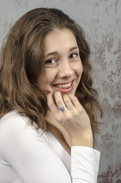  Portrait of a young brown-haired woman with a romantic curly hair in a white blouse  - Fotó, kép
