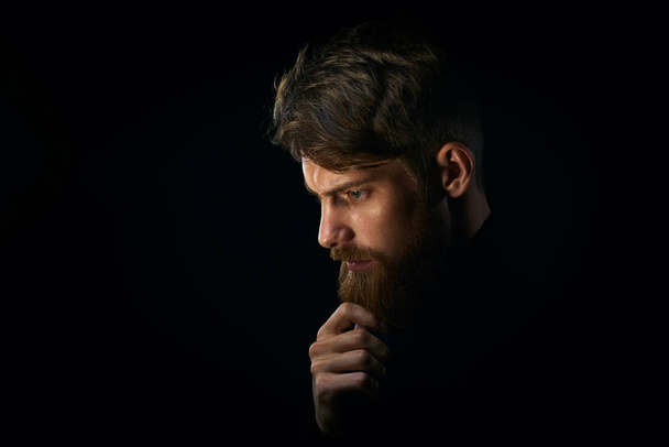 Close-up portrait of puzzled young man touching beard looking do - Foto, Bild