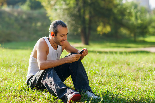 Guy listening to the player sitting on the grass - Fotoğraf, Görsel