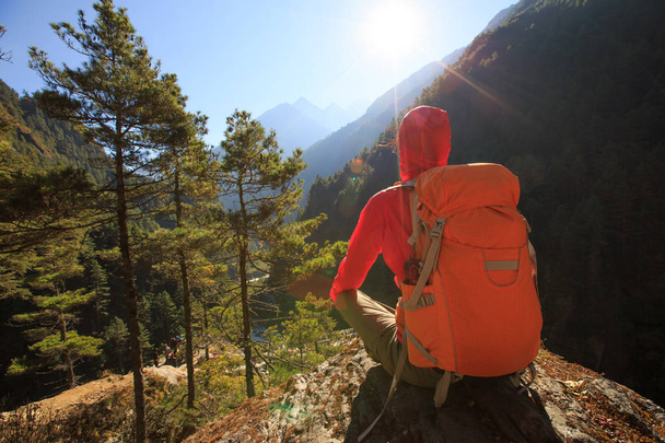 mujer con mochila sentado en el pico
  - Foto, imagen