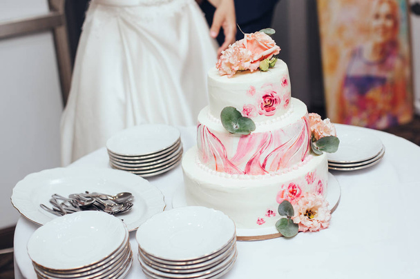 Sweet multilevel wedding cake on wedding banquet with pink rose  - Foto, Imagen