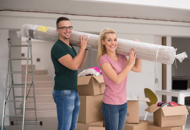couple portant un tapis emménageant dans une nouvelle maison
 - Photo, image