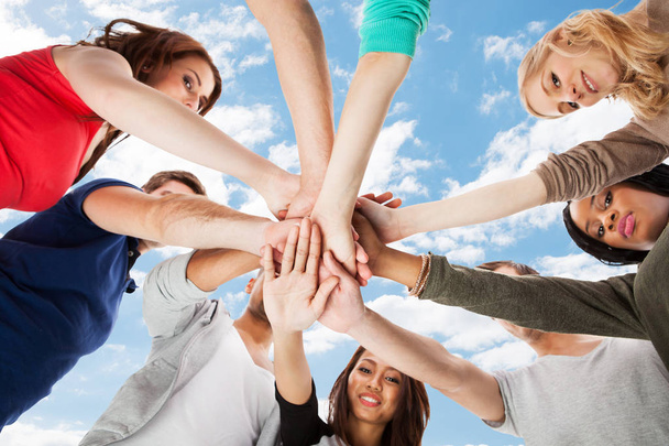 Low Angle View Of A Students Stacking Hands Against Sky - Foto, Imagen