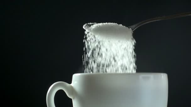 Azúcar blanco vertiendo de cuchara a taza blanca, primer plano cámara lenta hd video
 - Metraje, vídeo