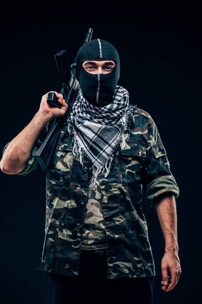 Terrorist attack. Terrorist with gun on black background - Photo, Image