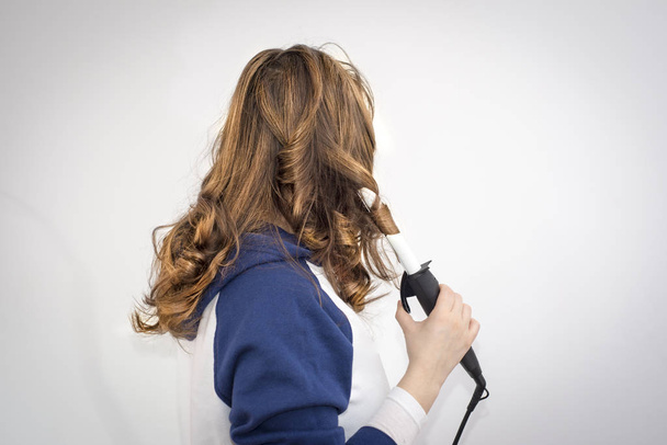 Donna Utilizzare un ferro arricciacapelli per arricciare i capelli
  - Foto, immagini