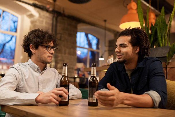 happy male friends drinking beer at bar or pub - 写真・画像