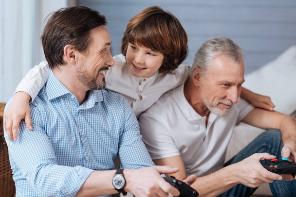 Cute positive boy standing behind his father and grandfather - Foto, Bild